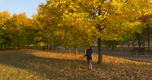 Petite fille blonde en béret Foulard rouge et veste saute et tire la branche de l'arbre tenant le bouquet fait de feuilles et de fleurs Faire un bouquet 