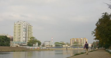 Sırt Çantası ile Man Park Alley Durur Asfalt yol tarafından Away Walking Away Bir Horizon Üzerinde Sırt Çantası Down Cityscape Çok Katlı Evler ve Köprü koyun