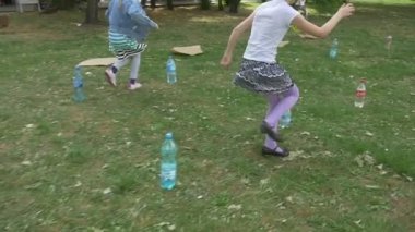 İki kız çimenler üzerinde şişe etrafında koşmak oynamak