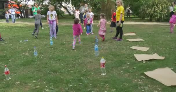 Pojke flicka spela spelet går runt flaskan på gräset, solig sommardag — Stockvideo