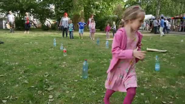 女の子プレイゲームは、草の上のボトルの周りに実行します — ストック動画