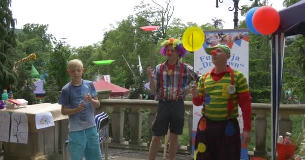 Clown in buntem Kostüm hilft Kindern auf Stelzen — Stockvideo