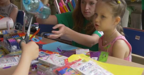 Niñas con animadores al aire libre en tienda Niñas Pintar imágenes en papel adultos ayudan — Vídeos de Stock
