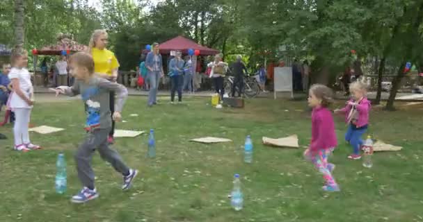 Pojke flicka spela spelet går runt flaskan på gräset, solig sommardag — Stockvideo