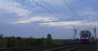 Sarı-Mavi tren hızlı demiryolu parça demiryolu kişi ağ üzerinde yoğun bulutlu gökyüzü sonbahar gün açık havada Opole Polonya yeşil ağaçlar şafak taşır