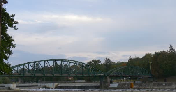 Ponte di ferro verde La gente va in bicicletta e cammina sul ponte Alberi verdi densi Cielo nuvoloso Mattina d'autunno — Video Stock