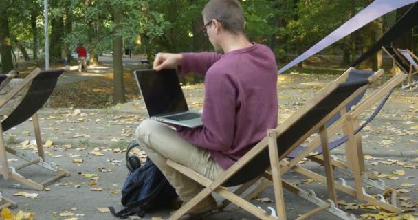 Mann nimmt Laptop aus seinem Rucksack öffnet ihn und beginnt freiberuflich Werbetexter Designer Buchhalter Programmierer Mann sitzt im Stuhl mit gekreuzten Beinen — Stockvideo