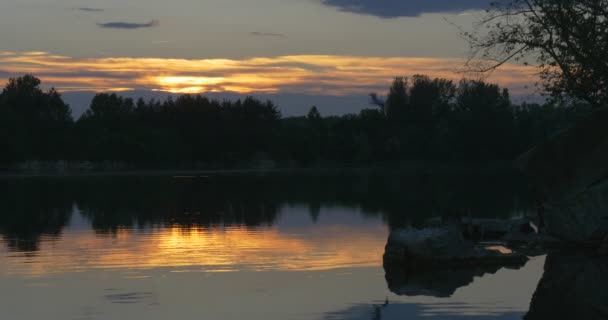 Ηλιοβασίλεμα στο ποτάμι, σιλουέτες των δέντρων και την αντανάκλαση του ουρανού στο νερό — Αρχείο Βίντεο