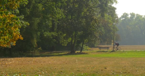 Homme Stnads avec vélo près du banc dans le parc, il obtient sur le vélo et se déplace homme en pantalon beige et chemise marron ensoleillé jour d'automne 