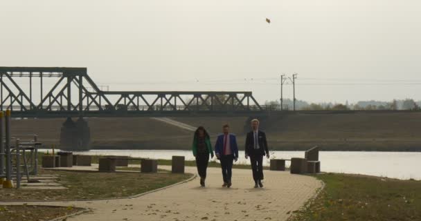 Twee mannen en vrouwen wandeling In het Park mannen In pakken en banden jongeman In blauwe Sport vest en broek loopt langs hen bewolkte herfst dag Opole, Polen — Stockvideo