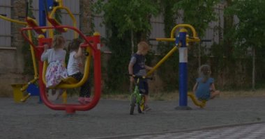 Pembe tişörtlü ve kot pantolonlu küçük bir kız oyun alanında eğleniyor.