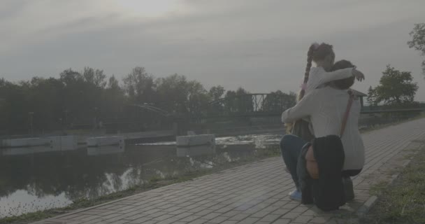 Niña rubia con trenza da un abrazo a su mamá Mujer en suéter blanco sostiene el ramo de hojas amarillas familia en Park Alley en el río — Vídeos de Stock