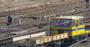 Workers in Orange Workwear Are Sitting in The Cabin of Yellow Locomotive Transporting the Load Machine is Moving by Railroad Junction Railway