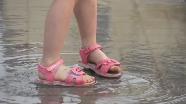 Twee kleine meisje gekleed in roze jurk in roze sandalen springt in de plas Slow Motion — Stockvideo