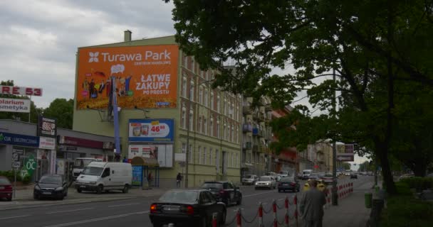 Mężczyzn pracowników w wieży Truck instalujesz pomarańczowy reklama Banner na metalowej ramie do czerwone bloki budynek droga gród samochody spaceru ludzi — Wideo stockowe