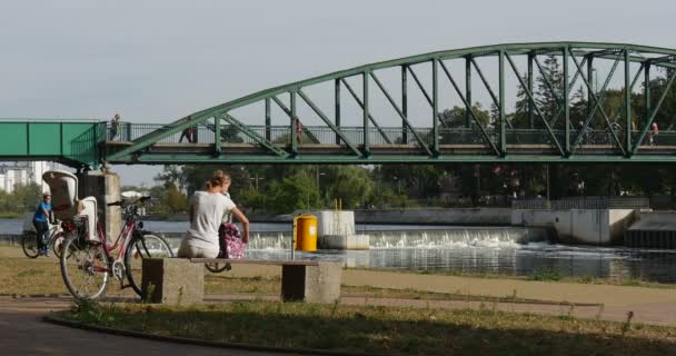 Mensen door fietsen gezinnen kinderen door fietsen vrouw met Babystoel op Bicycle Bridge via de rivier mensen hebben een Rest sport recreatie zonnige — Stockvideo