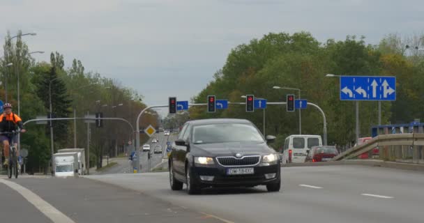 Jonge kerel In fiets helm rijdt op de fiets verschillende auto's gaan over de Steenweg Auto weg markering verkeersborden en lichten Crossroad Opole Polen — Stockvideo