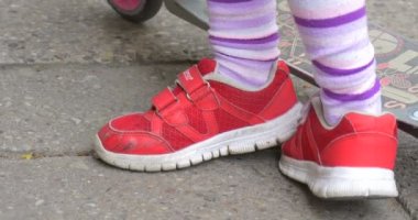 Kırmızı Spor Ayakkabı lı Etekli Bir Kick Scooter Kız Üzerinde Kız Street Inclines De Kick Scooter ile Close Up Onun El Bileziği ile Tekerlek Dokunur