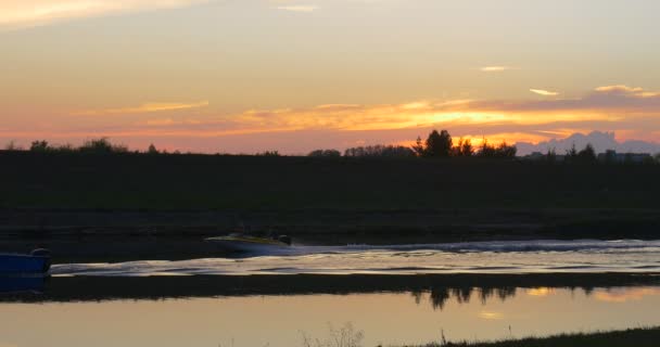 Motorboot is drijvende door rivier vijver Lake boot is verhuizen naar de links Horizon bomen silhouetten weide veld zonsondergang kabbelend Water Motor boot Trace — Stockvideo