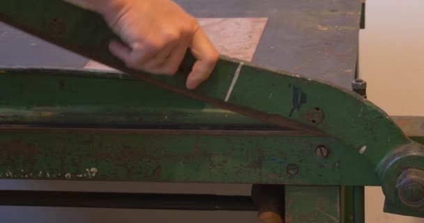 Las manos del hombre cortan la placa de cobre en la guillotina Instalación de la placa de cobre a la máquina de cerca Prepare la placa de cobre para el taller de grabado artesanal — Vídeos de Stock