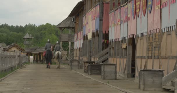 Trzech aktorów jak Vladimir wielki, Prince Vladimir i dwóch wojowników, żołnierzy w dawnych strojach są jazda daleko wzdłuż ściany starożytnego miasta — Wideo stockowe