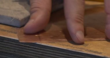 Adamın ellerini almak kare parça, bakır plaka kenarları kalem öğütmek için Başlat tablo hazırlamak üzerinde oyma resim yapmak için plakadır