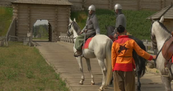 Drie acteurs als Vladimir de grote, prins Vladimir en twee krijgers, soldaten in oude kostuums, permanent, zittend op paarden op de brug — Stockvideo