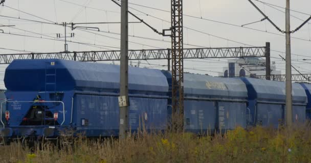 Голубые грузовые вагоны медленно перемещаются и останавливаются на железнодорожном пути Еще один грузовой поезд стоит на дальнем железнодорожном пути железнодорожной сети контакта — стоковое видео