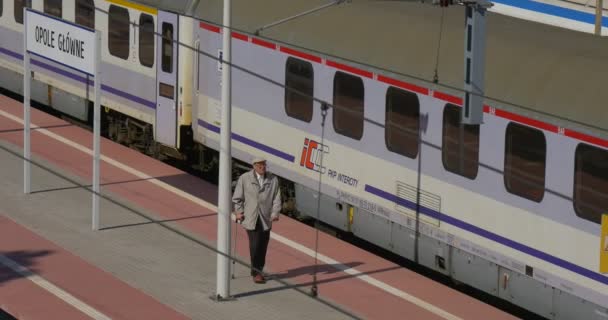 Starší muž s cukrovou třtinu se prochází po železnici společností Platform Train je stojící železniční stanice železnice železnice — Stock video