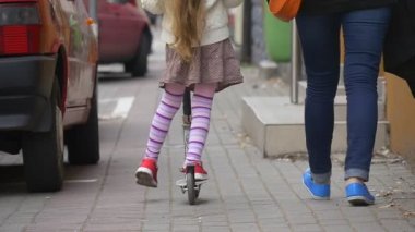 Sarışın Tüyleri ile Etek bir Kick Scooter Kız Kız Street Girl's Back Walking People Woman Mom Cars Slow Motion bir Kick Scooter Ridding olduğunu