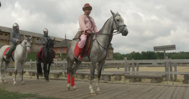 Актёры как князь Владимир Великий и двое его воинов едут верхом на лошадях по деревянной дороге — стоковое видео