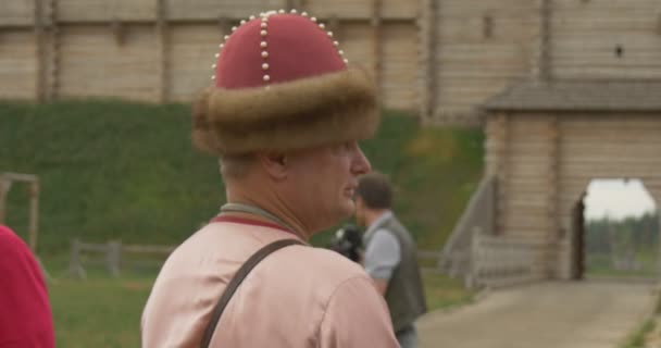 Actor en Pink Costune y Sombrero como el Príncipe Vladimir el Grande está parado frente al Arco de la Puerta de la Ciudad, Fotógrafo — Vídeo de stock