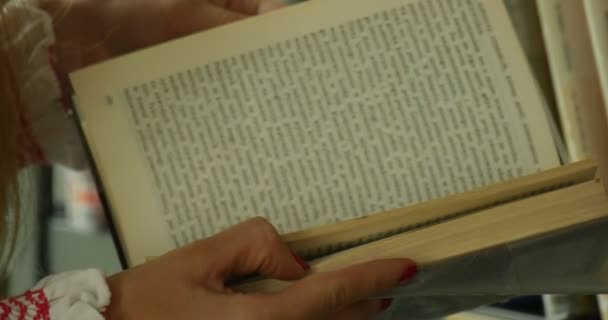 Woman's Hands With Book Woman With Long Hair In Embroidered White Shirt Browses The Book Close View John Paul II Municipal Public Library In Opole Poland — Stockvideo