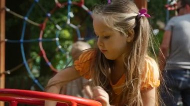 Bir salıncak küçük kız ile uzun adil kıllar turuncu tişört üzerinde pembe Tilda Swinging parkta oynarken onun oyuncak tavşan ile Swaying kızdır