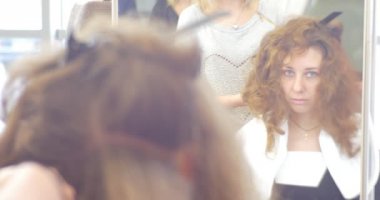 Modelin yansımasıdır ayna stilist Kuaför içinde yapım saç modeli oluklu demir için bir kadın uzun kıllar Berber Güzellik salonları ile tarafından