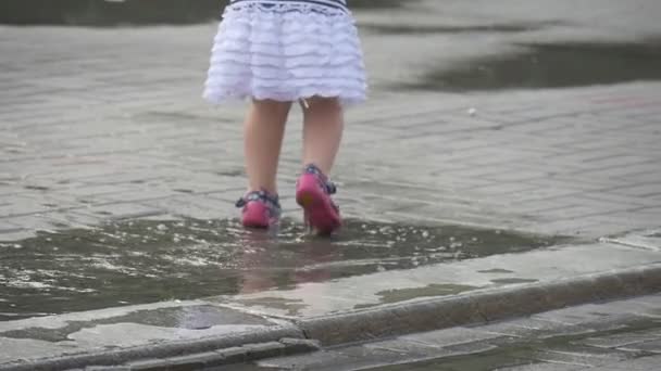 Маленькая девочка в летней одежде играет на улице — стоковое видео