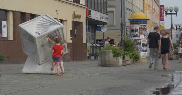 Дві дівчини переглянути великий білий кубічних скульптуру, яка стоїть просто неба на вулиці. — стокове відео