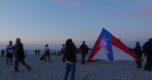 Οι άνθρωποι είναι που φέρουν πολύχρωμα φωτεινά Kite απόγευμα λαμπρό λαμπτήρες μπλε ουρανό νυκτερινές πτήσεις φωτεινή χαρταετούς σε το Kite Φεστιβάλ Leba Πολωνία — Αρχείο Βίντεο