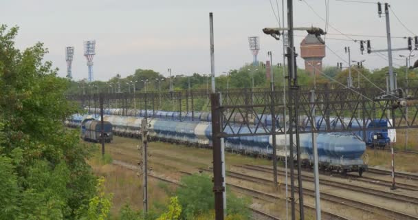 Locomotiva se move na trilha ferroviária Dois trens de carga estão na ferrovia Suportes da ferrovia Contato Posts da lâmpada de rede Luzes de entrada Dia chuvoso — Vídeo de Stock