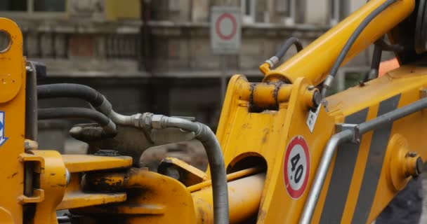 Bewegende graafmachine Scoop close-up werknemers mannen in oranje werkkleding en helmen bestuurder bewegende gele graafmachine Road Repair bestrating van de weg City Street — Stockvideo