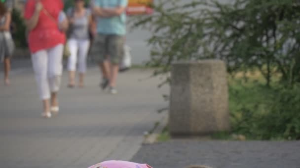 Het meisje in een roze sundress speelt met water in de straat — Stockvideo