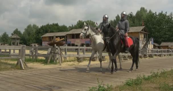 Aktorzy w Prince Vladimir wielki, chrzcicielem Rosji i dwóch jego wojowników jadą na ich konie przez drewniany most do drewnianych starożytnych Sity — Wideo stockowe