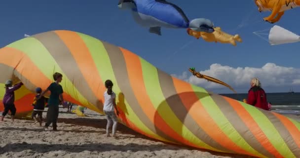 Bambini che spingono in aria un nuotatore di aria conica colorata, cercando di farlo prendere dal vento durante il festival internazionale degli aquiloni a Leba, Polonia . — Video Stock