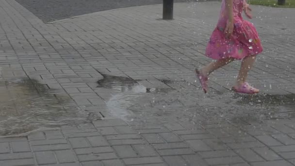 La chica corre por los charcos en el centro del parque de la ciudad — Vídeo de stock