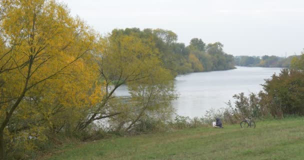 Людина в теплих по якому тече р капелюх людина в теплих куртка фрілансера програміст копірайтер дизайнер бухгалтер сидить на березі з ноутбук працює — стокове відео