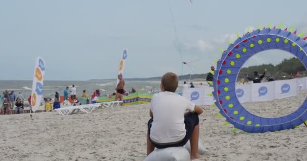 Um menino voando um papagaio - Pessoas preparando seus papagaios e nadadores de ar ou voando-os no festival internacional de papagaios em Leba, Polônia . — Vídeo de Stock