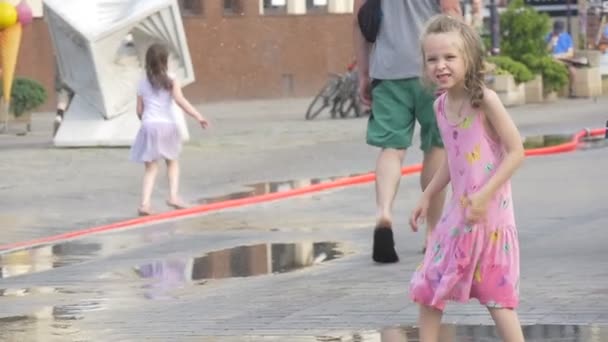 Twee kleine meisjes spelen in een plas — Stockvideo