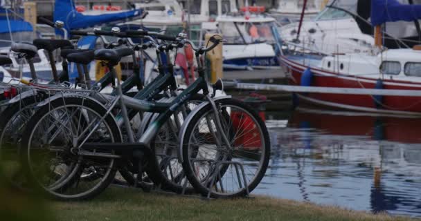 Cykelparkeringar på gräs Yacht Club hamnen båtar läggs upp Safe Harbor lugnt vatten molnig sommardag — Stockvideo
