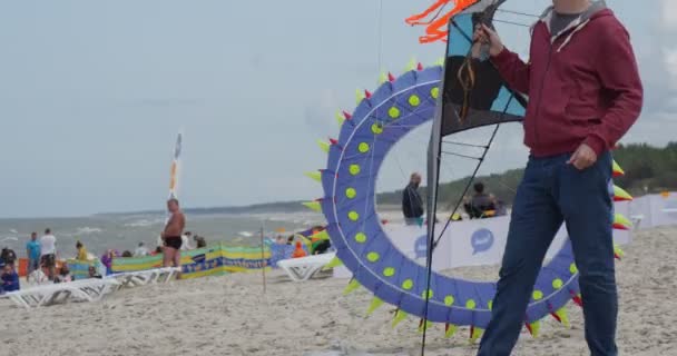 Divers cerfs-volants - personnes préparant leurs cerfs-volants et nageurs aériens ou les volant sur le festival international de cerf-volant à Leba, Pologne . — Video