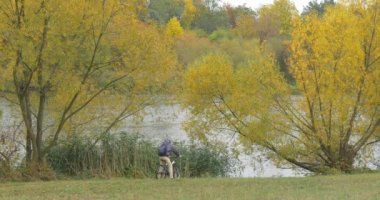 İçinde Ushanka şapka ve ceket gelir bisikletle göl nehir Bisiklet oturur yerle görüştüm ve onun sırt çantası sonbahar açma bankaya adam